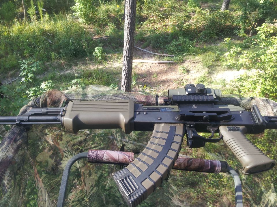 Saiga-style AK rifle with optic and drum-style magazine in tree stand
