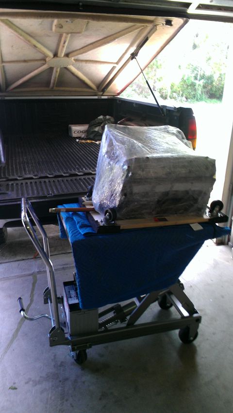 2005 Chevrolet Suburban - Engine wrapped in plastic on a dolly being loaded into the bed of a pickup truck.