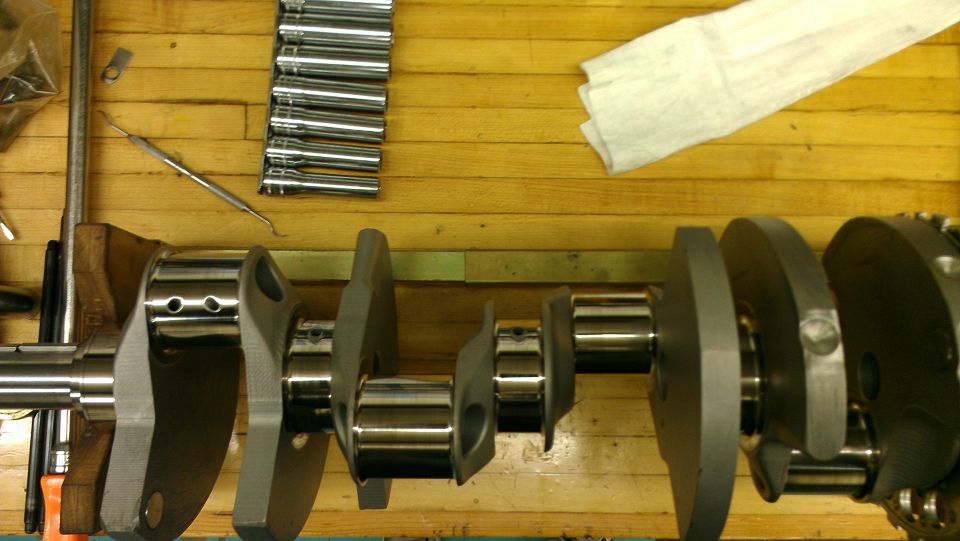 Crankshaft on a wooden workbench with a set of socket extensions and a rag