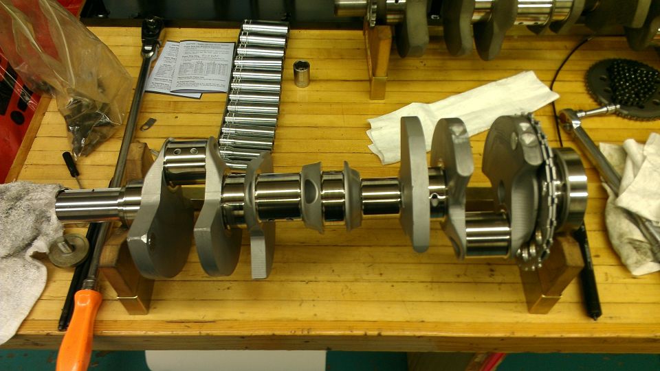 Crankshaft on wooden workbench with tools and a socket set