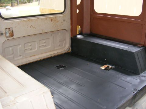 Vehicle interior cargo area with black floor mat and white paneling