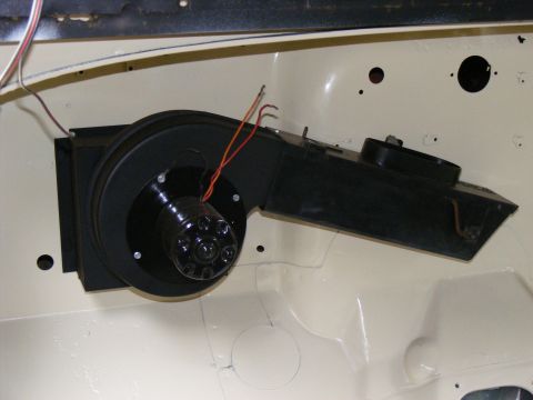 HVAC blower motor assembly with wires connected, mounted in vehicle interior
