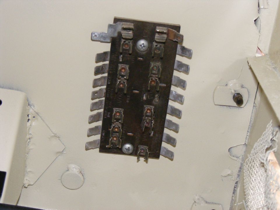 Close-up of an electrical component with many metal terminals and screw mounts