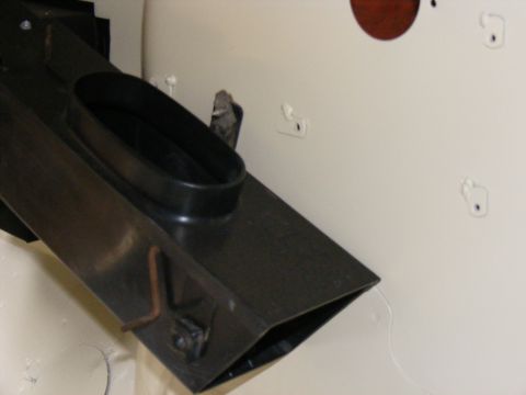 Black air duct with oval opening, attached to a cream-colored surface