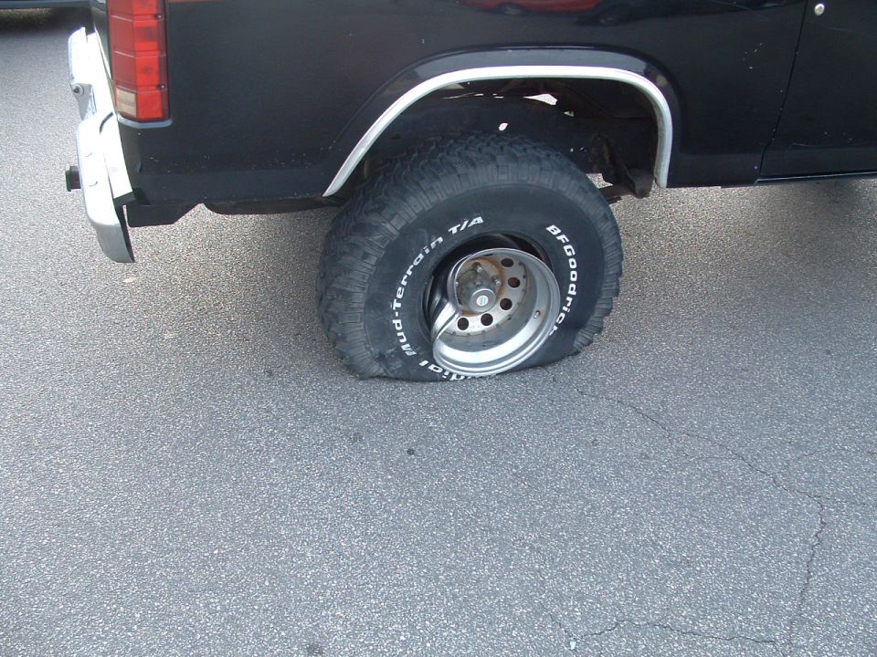 Rear corner of a black lifted truck on a BFGoodrich All-Terrain tire and slotted alloy wheel