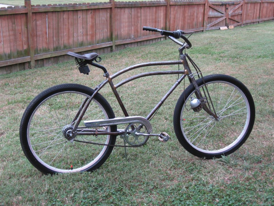 Rusty bicycle with a brown leather seat and a silver chain guard, viewed from the side