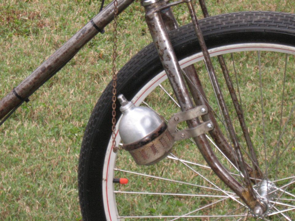 Close-up of a bicycle's front fork, showing a metal headlight and spokes