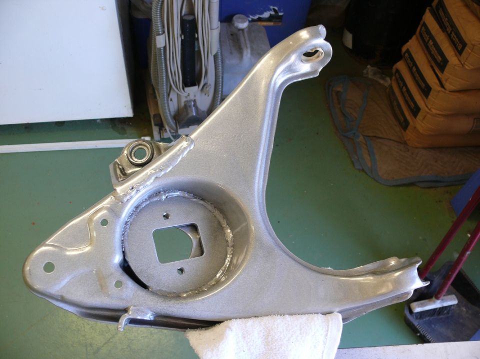 Silver automotive suspension control arm with a square cutout and a bearing assembly