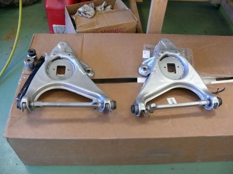 Pair of silver control arms on cardboard box