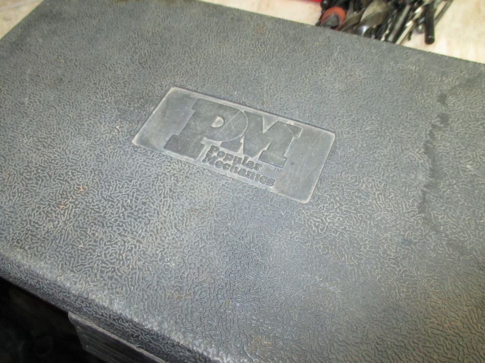 Gray textured plastic tool case with 'PM Popular Mechanics' logo embossed on lid