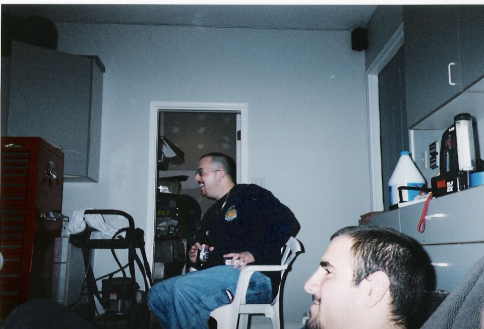 People hanging out in a garage with a red tool chest and cabinets