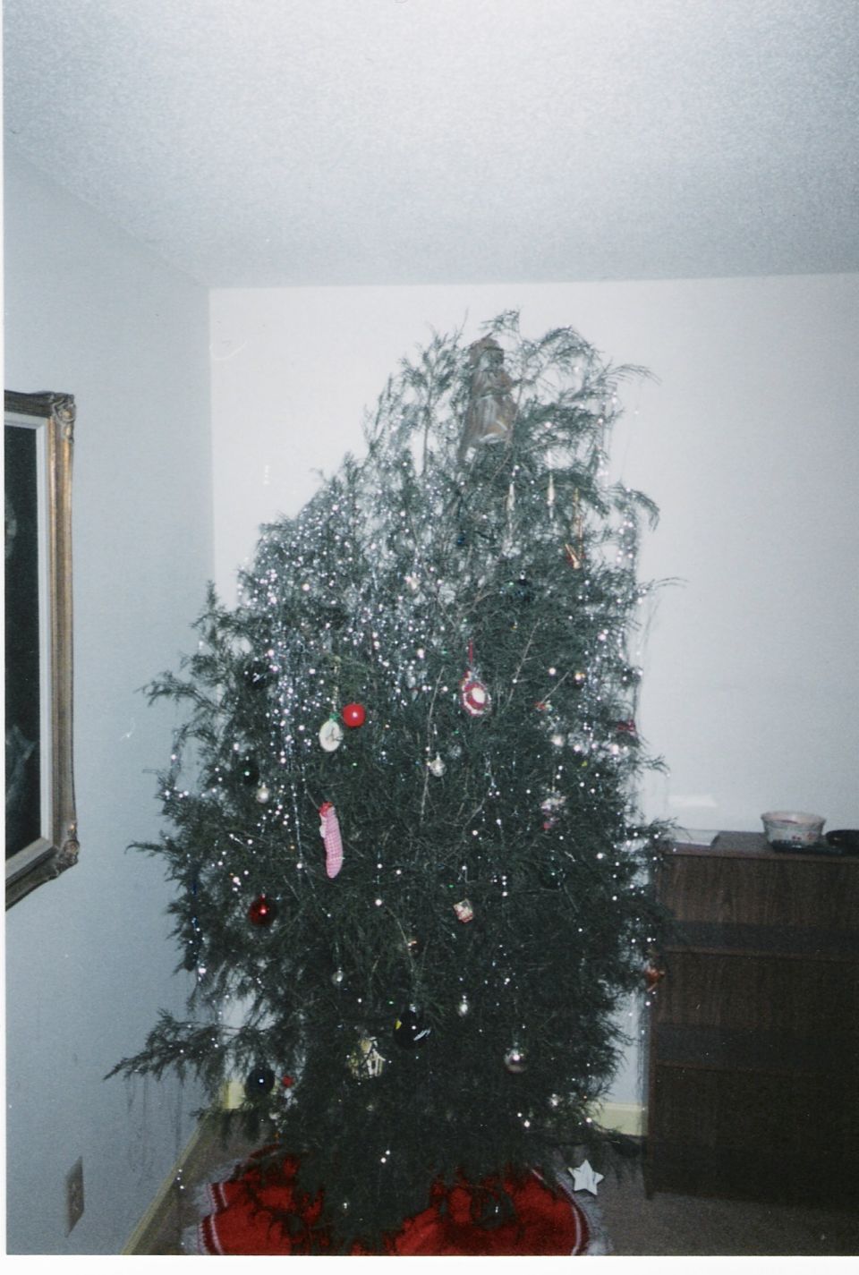 Decorated Christmas tree in the corner of a room on a red tree skirt