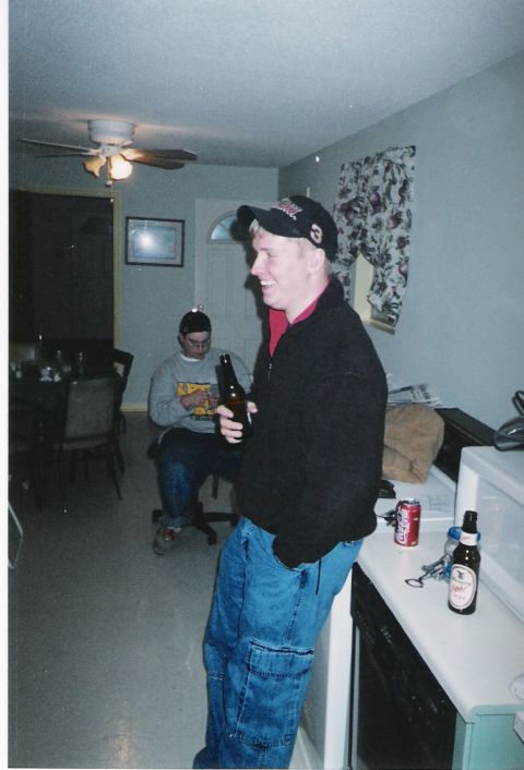 1977 Ford Mustang II - Two men are in a room, one holding a beer and wearing a baseball cap, while another sits in a chair in the background.