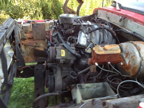 1978 Ford Bronco - The engine bay of a vehicle shows signs of rust and wear, with various components visible.