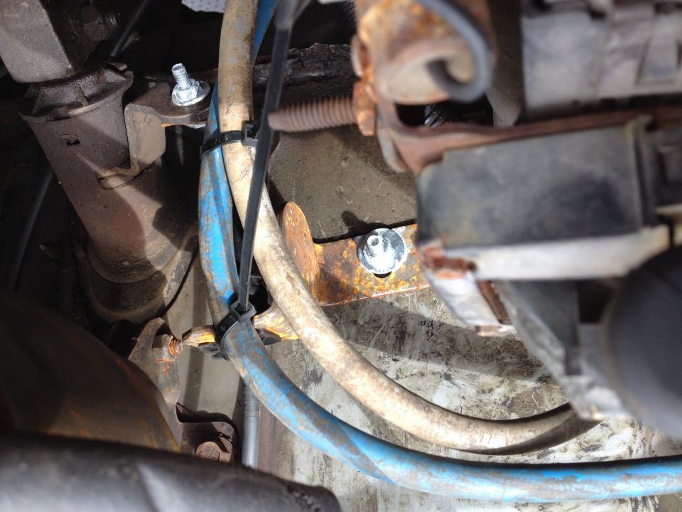 Close-up of engine bay with hoses and a bolted bracket.