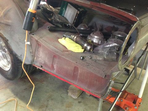 1964 Ford Fairlane - Close-up of a car's fender well and engine bay, showing disassembled parts and a work light.