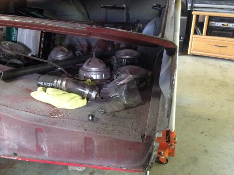 1964 Ford Fairlane - Interior view of a car's trunk area, filled with assorted automotive parts and a yellow cloth.