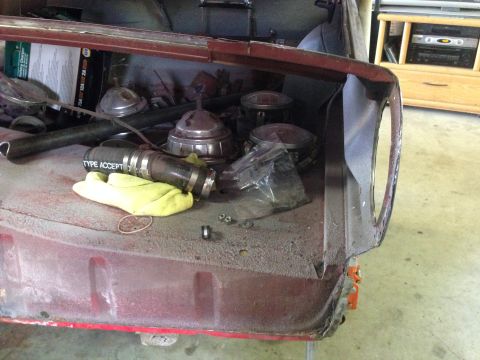 1964 Ford Fairlane - The trunk interior holds various parts, including an air cleaner assembly, a hose with "TYPE ACCEPT" visible, and a yellow glove.