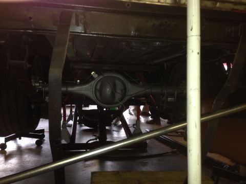 1964 Ford Fairlane - Underside view of a vehicle's rear axle assembly and suspension parts being worked on.