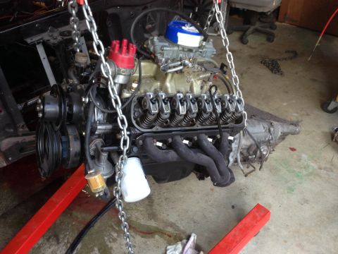 1964 Ford Fairlane - A V8 engine and transmission assembly is suspended by chains, ready for installation or repair.