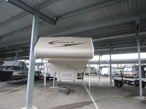 2008 Ford F-450 - A truck camper is parked under a covered lot alongside other vehicles and a boat.