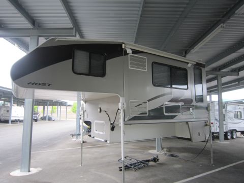 2008 Ford F-450 - A Host truck camper is shown parked under a covered structure, with another trailer visible in the background.