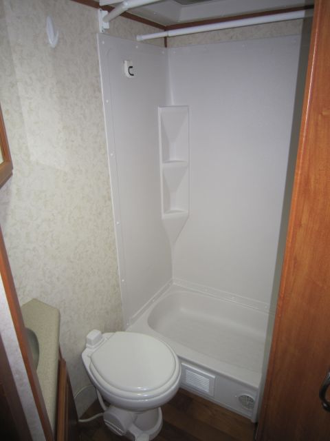 2008 Ford F-450 - The interior of an RV shows a compact bathroom with a toilet and a separate shower stall.
