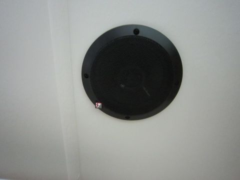 2008 Ford F-450 - A round black speaker is installed in a white ceiling or wall surface.