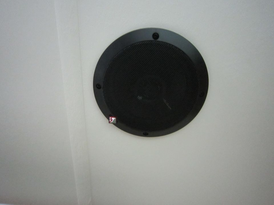Round black ceiling speaker mounted in a white surface
