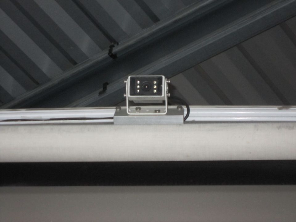 Security camera mounted on a metal rail under a corrugated metal ceiling