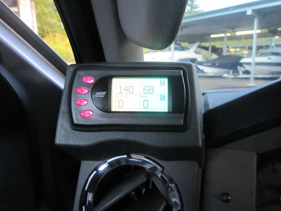 Digital gauge display with pink buttons showing 140 and 68, mounted in a vehicle interior