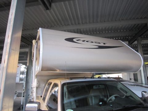 2008 Ford F-450 - A truck camper unit is mounted on a pickup truck, parked next to another vehicle.
