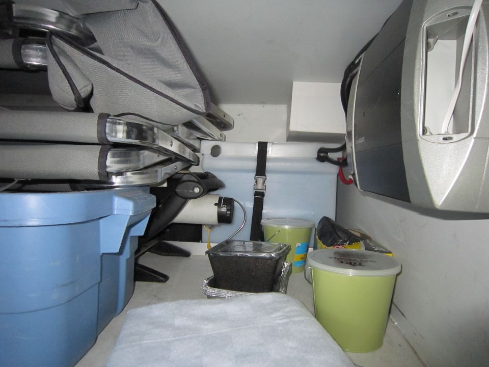 Interior view of a vehicle's storage area with blue and green bins, folded seats, and equipment