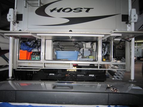 2008 Ford F-450 - Storage compartments of a truck camper are open, revealing organized and unorganized items within.