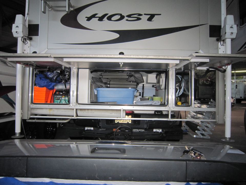 Truck camper storage compartments with various items inside. A blue bin is visible in the center compartment