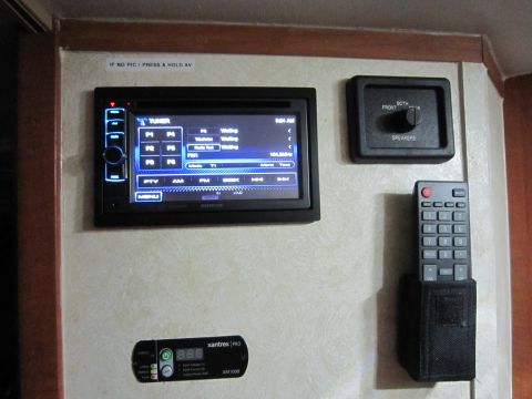 2008 Ford F-450 - A close-up view of an RV's interior electronics panel, a Kenwood stereo, speaker controls, remote, and battery monitor.