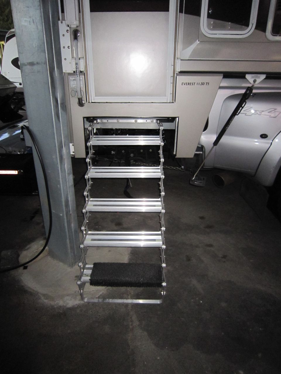 Silver camper steps with black tread on a truck bed