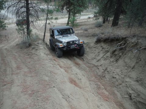 2005 Jeep Wrangler - A silver 2005 Jeep Wrangler navigates a sandy incline, equipped with a winch for off-road challenges.