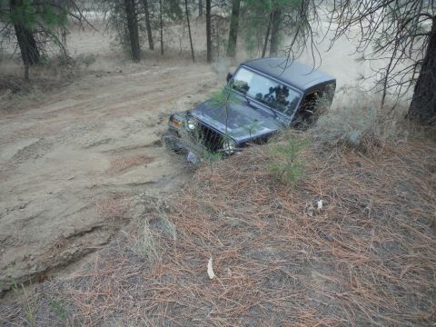 2005 Jeep Wrangler - A dark Jeep Wrangler struggles on a muddy trail during an off-road excursion.