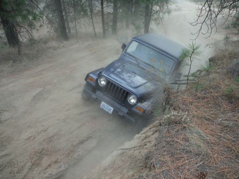 2005 Jeep Wrangler - 2005 Jeep Wrangler driving on a dirt trail, kicking up dust.