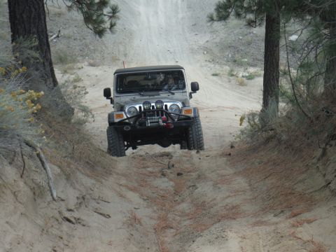 2005 Jeep Wrangler - Jeep Wrangler navigates a challenging dirt track in a wooded area.