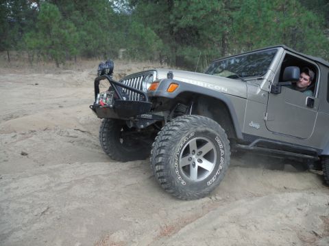 2005 Jeep Wrangler - A silver 2005 Jeep Wrangler navigates a sandy trail, its off-road modifications.