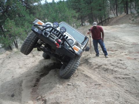 2005 Jeep Wrangler - A Jeep Wrangler navigates a steep, sandy incline with a person observing the maneuver.