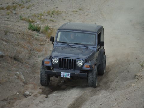 2005 Jeep Wrangler - A dark blue 2005 Jeep Wrangler navigates a dusty off-road trail.