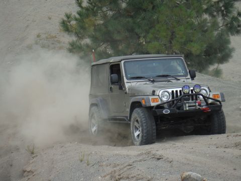2005 Jeep Wrangler - A silver Jeep Wrangler Rubicon drives on a dusty off-road trail.