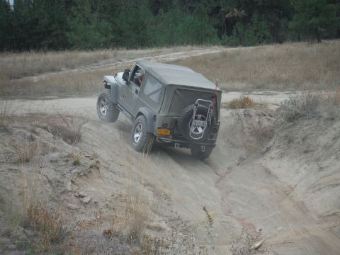 2005 Jeep Wrangler - Olive green 2005 Jeep Wrangler navigates an off-road trail, climbing a steep dirt incline.