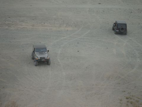 2005 Jeep Wrangler - Two Jeep Wranglers traverse a dusty, open terrain.