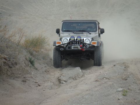2005 Jeep Wrangler - A silver 2005 Jeep Wrangler navigates a dusty, off-road trail, kicking up a cloud of dirt.