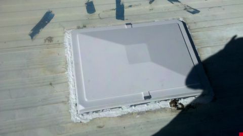 1997 Dodge 3500 - A white RV roof vent is sealed with caulk onto a corrugated metal surface.