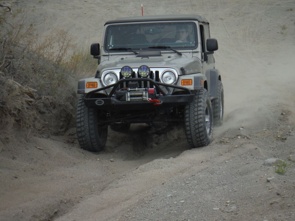 2005 Jeep Wrangler driving on a dirt trail, kicking up dust